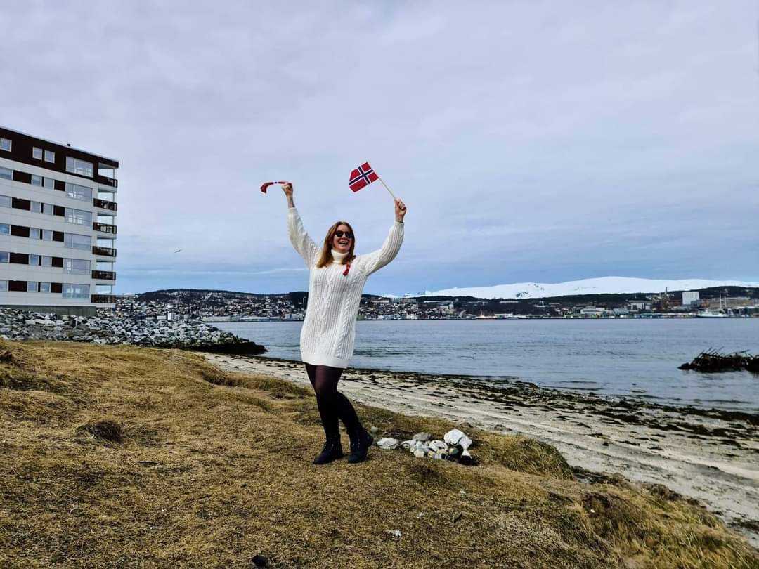 Bilde av WIbeke foran vann mens hun holder norske flagg i luften