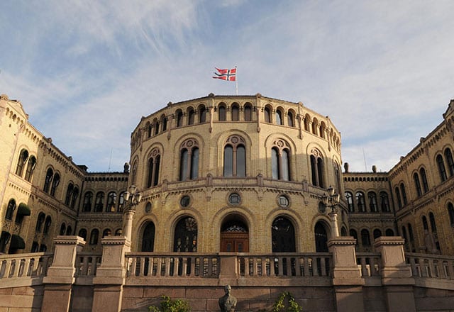 Bilde viser det norske stortingets fremside. Flagget er heist på toppet av bygningen. Kan brukes for å illustrere politikk og politiske skriv.