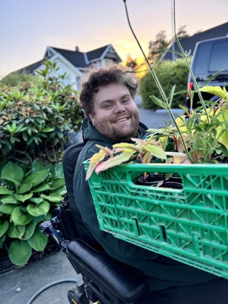 Bilde av Aleksander Olsen Vollebekk som sitter med en stor blomsterkasse i fanget.